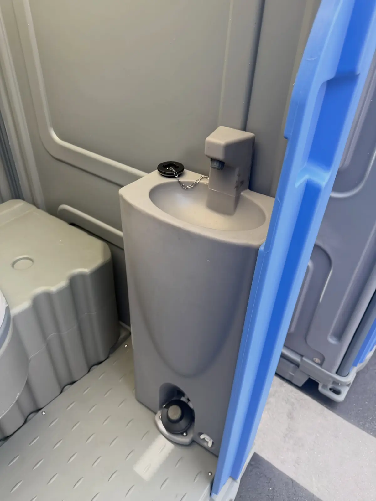 Inside a flushing porta potty with a foot-pump hand sink