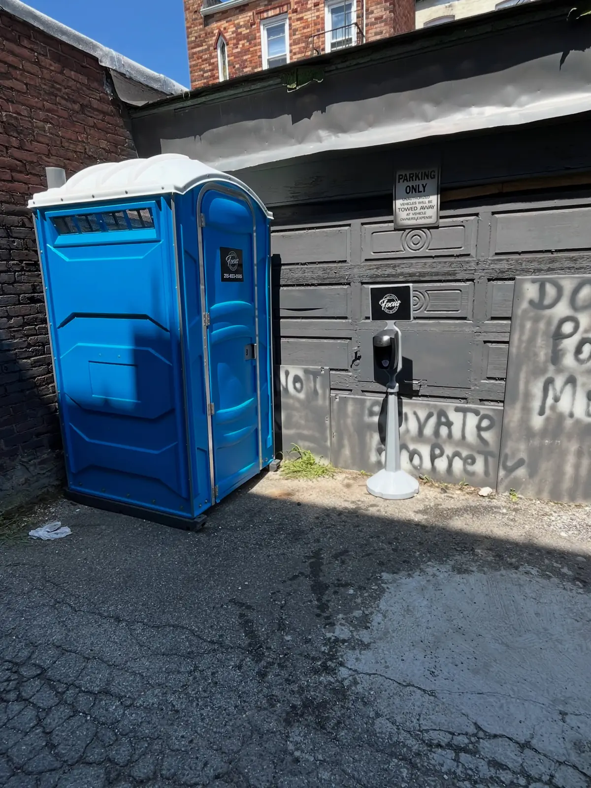Blue portable toilet and sanitizer stand on a jobsite