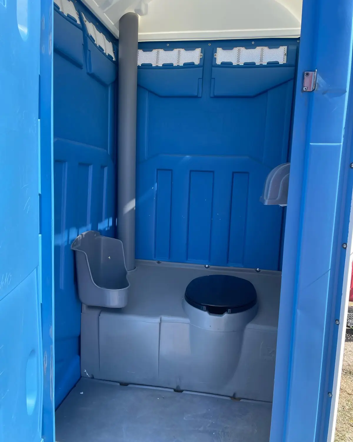 Inside a standard porta potty with toilet seat, urinal and vent pipe